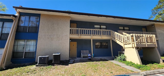 rear view of house featuring cooling unit and stucco siding