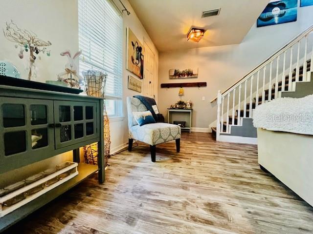 11607 NW 18th Pl, Gainesville, FL 32606 - living area featuring visible vents, baseboards, wood finished floors, and stairway