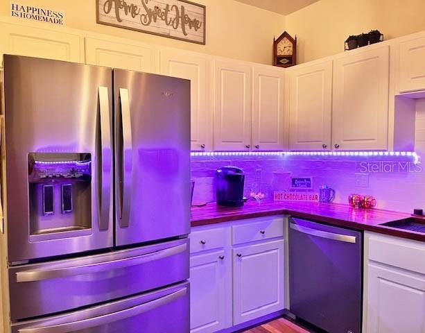 11607 NW 18th Pl, Gainesville, FL 32606 - kitchen with white cabinets, backsplash, dark countertops, dishwashing machine, and stainless steel refrigerator with ice dispenser