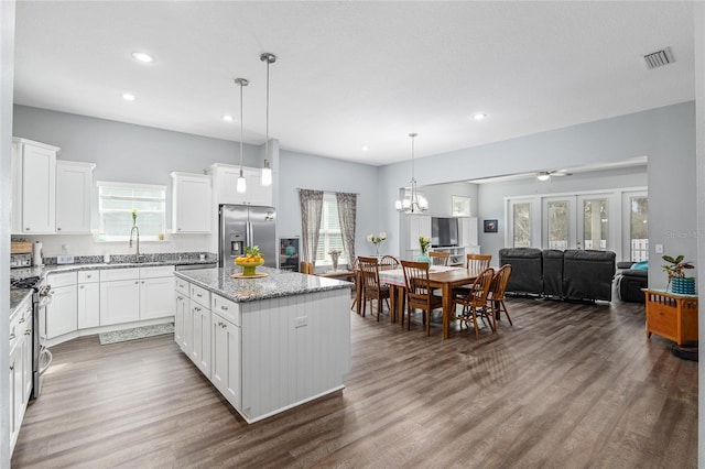 kitchen featuring white cabinetry, a kitchen island, pendant lighting, stainless steel appliances, and light stone countertops
