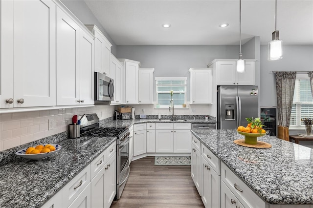 kitchen with stainless steel appliances, sink, white cabinets, and decorative light fixtures