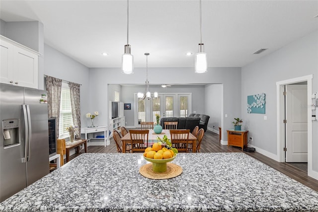 kitchen featuring decorative light fixtures, white cabinetry, stainless steel fridge, a center island, and light stone countertops