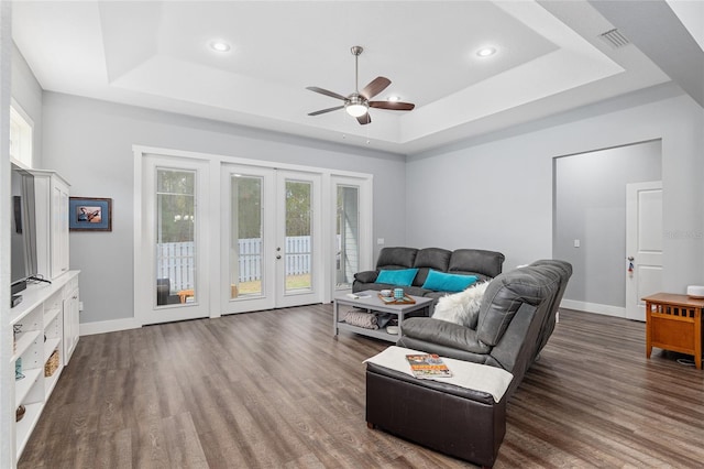 living room featuring french doors, a healthy amount of sunlight, a tray ceiling, and dark hardwood / wood-style flooring