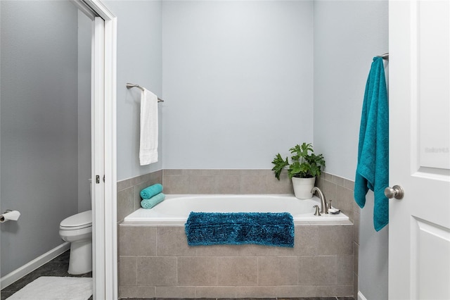 bathroom featuring tiled bath and toilet