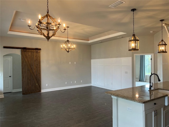 kitchen featuring a tray ceiling, visible vents, an inviting chandelier, and a barn door