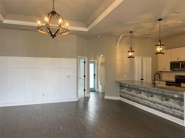 kitchen featuring arched walkways, a raised ceiling, stainless steel microwave, a sink, and black / electric stove