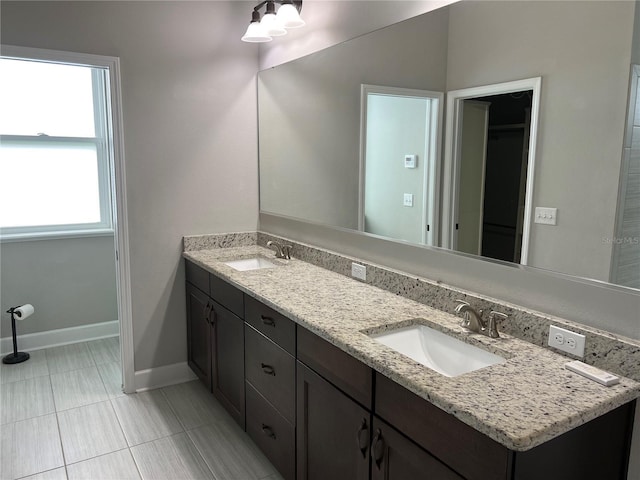 bathroom featuring a sink, baseboards, and double vanity