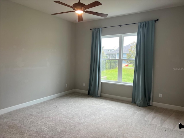 carpeted spare room featuring ceiling fan and baseboards