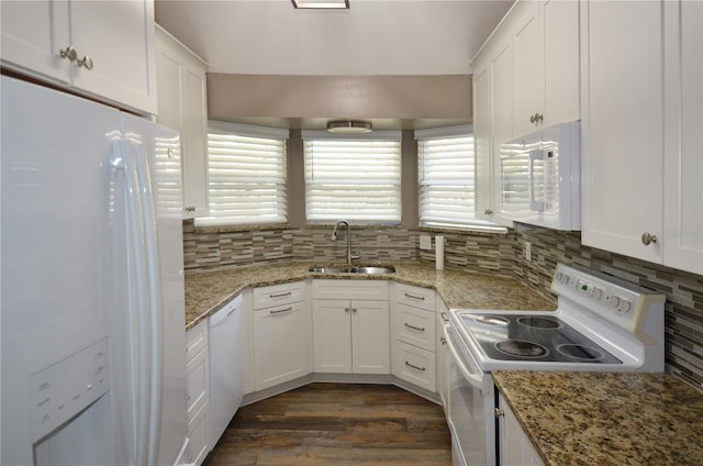 kitchen with white appliances, white cabinetry, light stone counters, and a sink