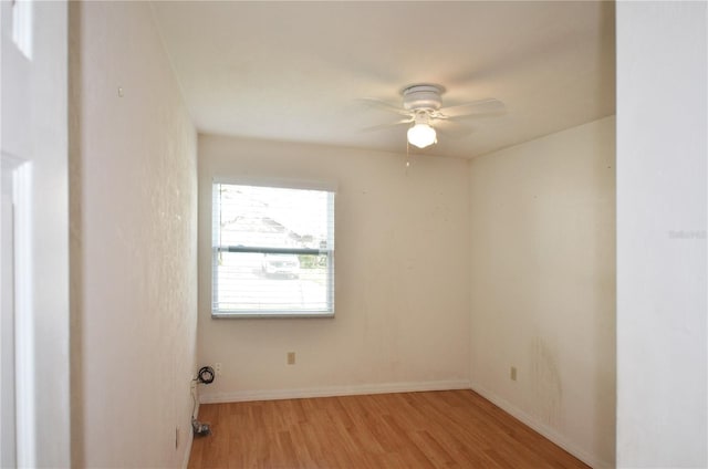 empty room with a ceiling fan, light wood-style flooring, and baseboards