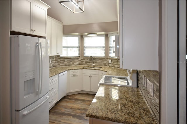 kitchen featuring white appliances, light stone counters, white cabinets, and a sink