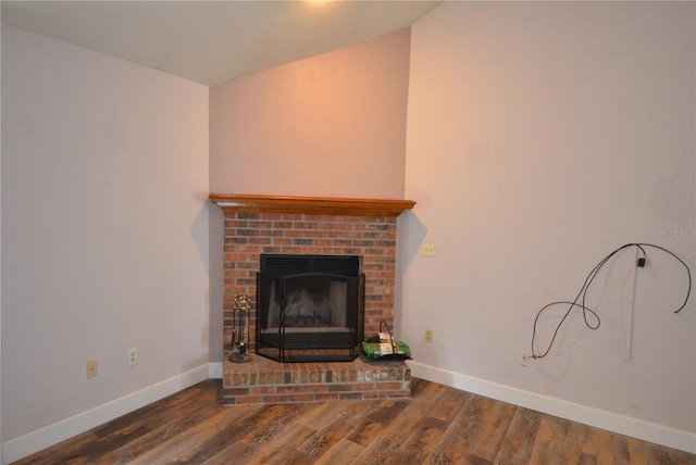unfurnished living room with a brick fireplace, dark wood finished floors, and baseboards
