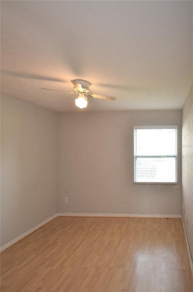 empty room featuring light wood-style floors, baseboards, and a ceiling fan