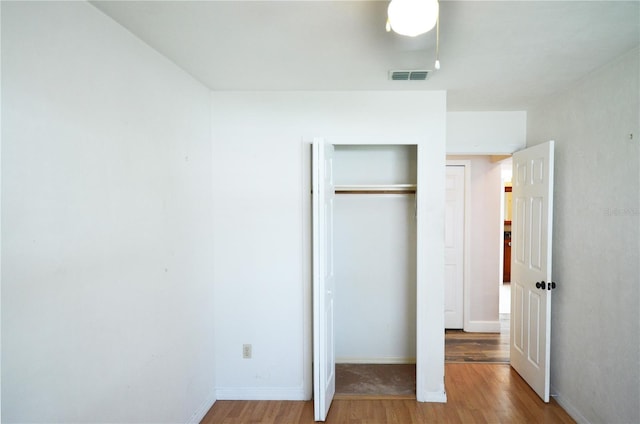 unfurnished bedroom featuring light wood-style floors, baseboards, visible vents, and a closet