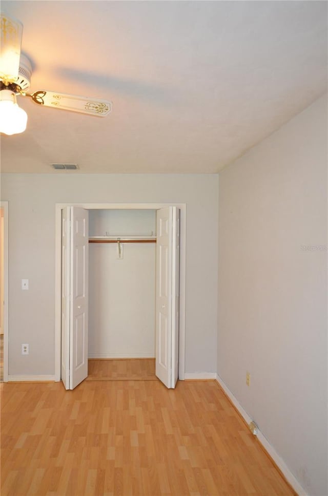 unfurnished bedroom featuring light wood-type flooring, baseboards, visible vents, and a closet