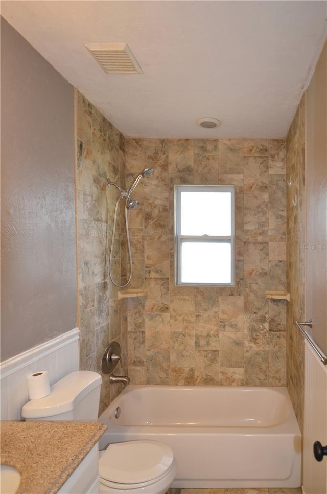 full bathroom featuring visible vents, toilet, washtub / shower combination, wainscoting, and vanity