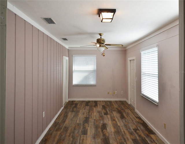 unfurnished room featuring dark wood-style flooring, visible vents, and plenty of natural light
