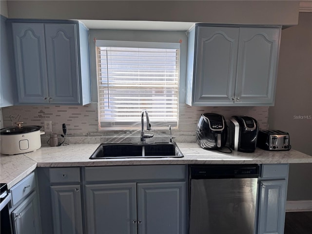 kitchen with sink, decorative backsplash, gray cabinets, and stainless steel dishwasher