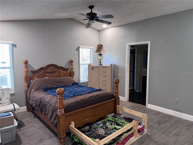 bedroom featuring vaulted ceiling, hardwood / wood-style floors, multiple windows, and a textured ceiling