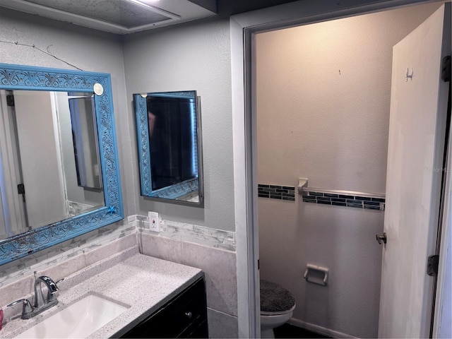 bathroom featuring vanity, tile walls, and toilet