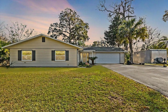 ranch-style house with an attached garage, driveway, and a front lawn