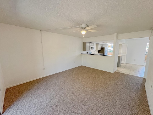 unfurnished living room with light colored carpet, a textured ceiling, and ceiling fan