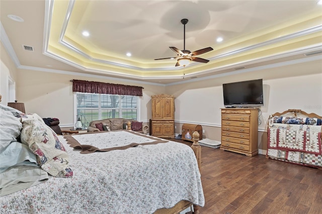 bedroom with crown molding, dark wood-type flooring, ceiling fan, and a tray ceiling