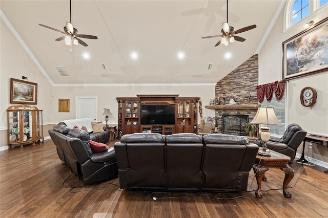 living room with hardwood / wood-style flooring, crown molding, and a stone fireplace