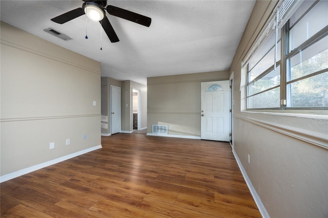 unfurnished living room featuring ceiling fan, dark hardwood / wood-style floors, and a textured ceiling