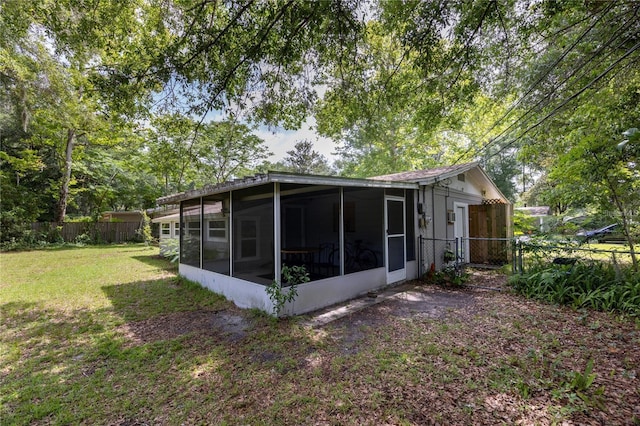 back of property with a sunroom and a yard