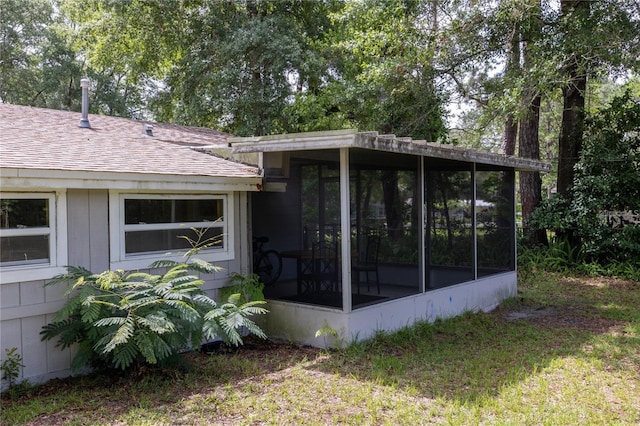 view of home's exterior featuring a sunroom and a lawn