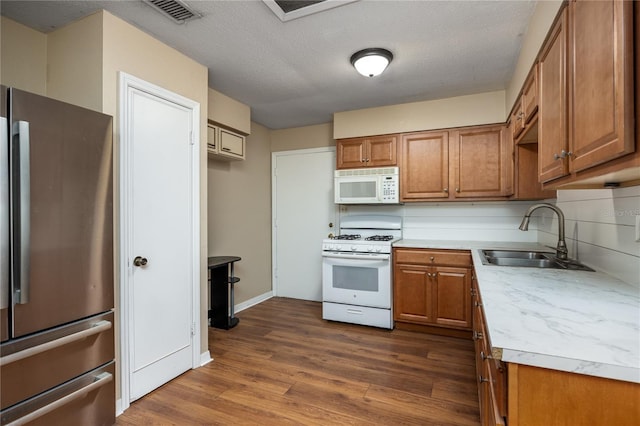 kitchen with white appliances, dark hardwood / wood-style flooring, sink, and a textured ceiling