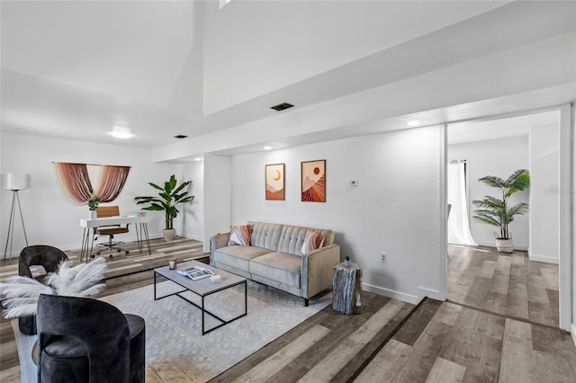 living room featuring hardwood / wood-style flooring and a towering ceiling