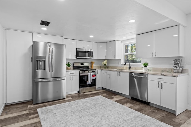 kitchen featuring stainless steel appliances, white cabinetry, sink, and dark hardwood / wood-style flooring