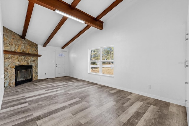 unfurnished living room featuring beam ceiling, high vaulted ceiling, light wood-type flooring, and a fireplace