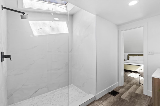 bathroom featuring hardwood / wood-style flooring, tiled shower, and a skylight