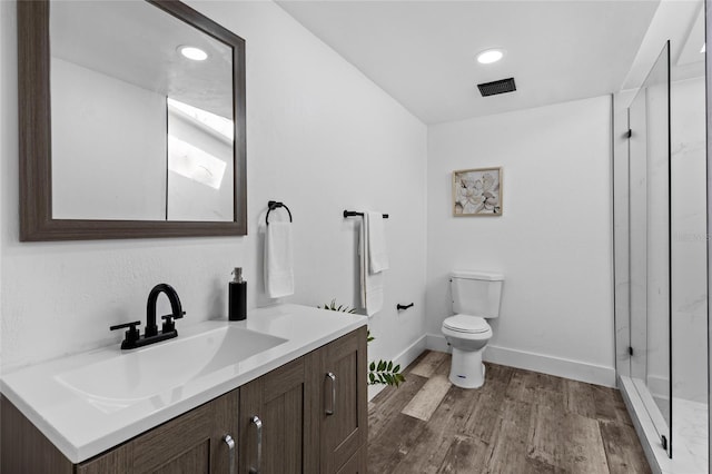 bathroom featuring wood-type flooring, walk in shower, vanity, and toilet