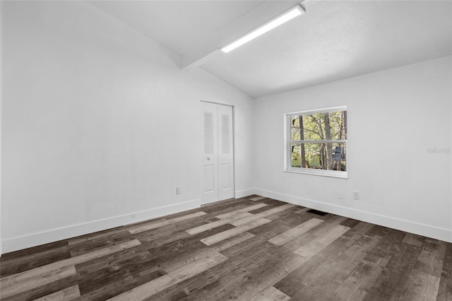 empty room with dark hardwood / wood-style flooring and vaulted ceiling with beams