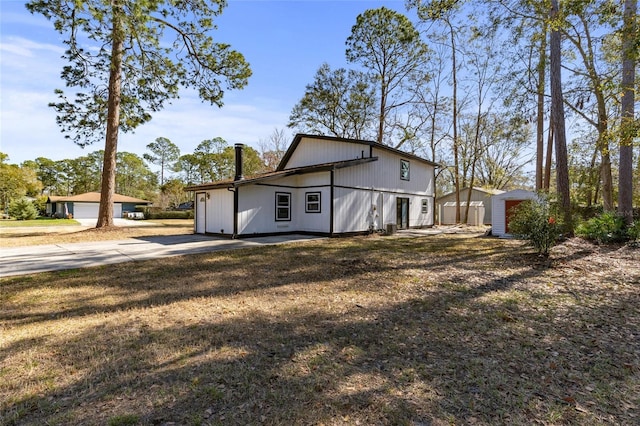 view of property exterior with a storage unit, a yard, and a garage