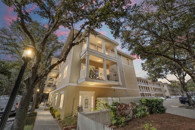 property exterior at dusk featuring a balcony and central AC unit