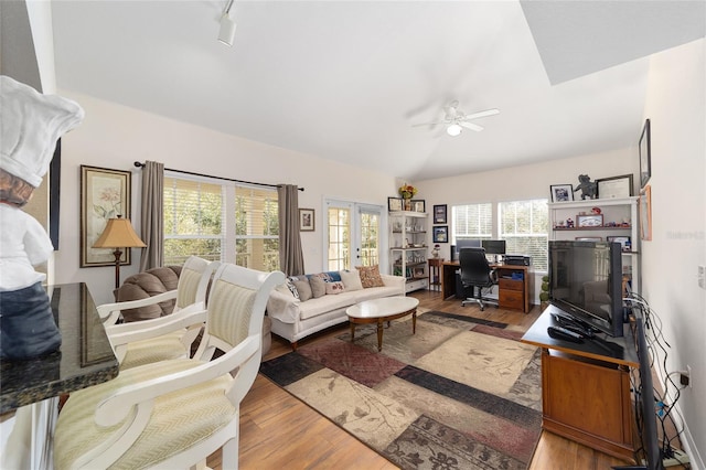 living room featuring hardwood / wood-style flooring, ceiling fan, track lighting, vaulted ceiling, and french doors