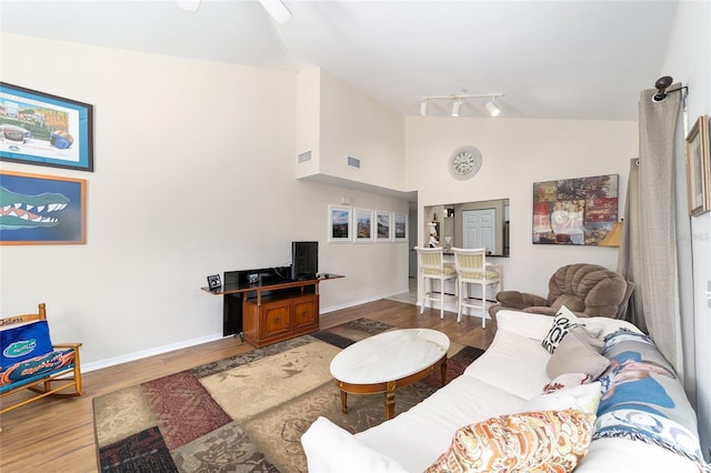 living room with hardwood / wood-style floors, track lighting, and high vaulted ceiling