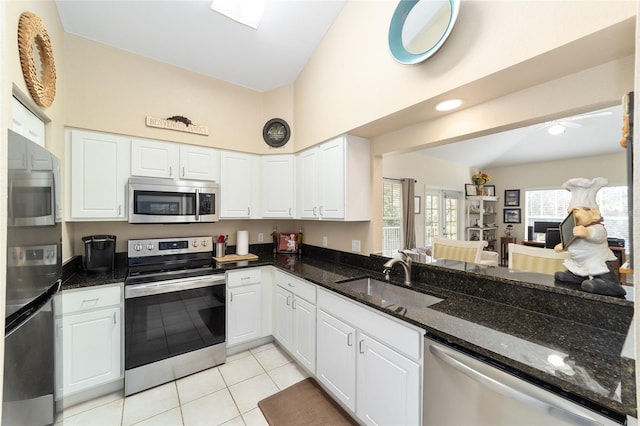 kitchen with stainless steel appliances, white cabinetry, sink, and dark stone countertops