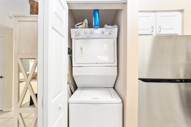 laundry area with stacked washer / dryer and light tile patterned floors