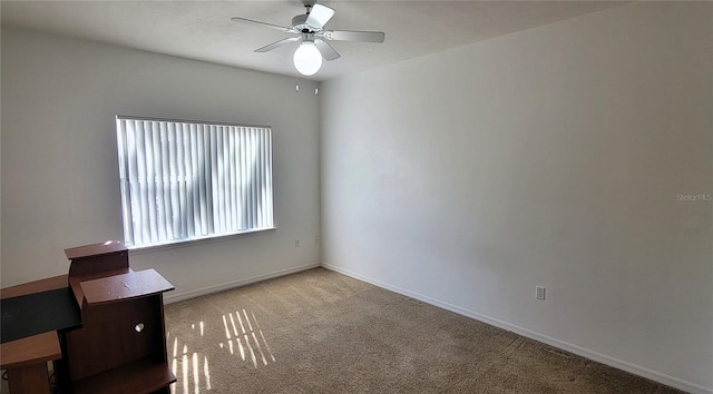 spare room featuring light carpet, a ceiling fan, and baseboards