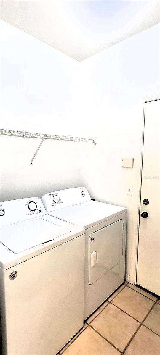 washroom with washer and clothes dryer and light tile patterned flooring