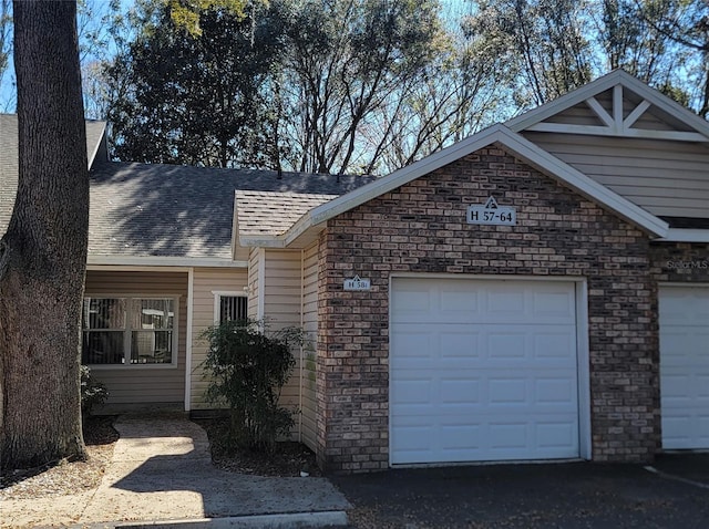 single story home featuring a garage, brick siding, and roof with shingles