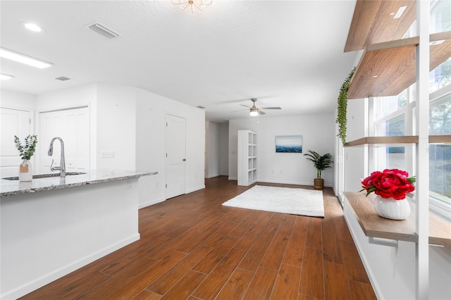 unfurnished living room with dark hardwood / wood-style floors, sink, and ceiling fan