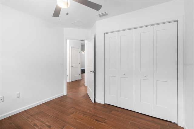 unfurnished bedroom with dark wood-type flooring, a closet, and ceiling fan