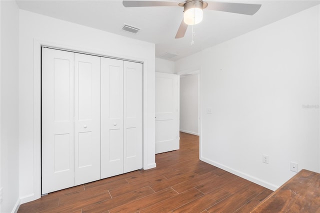 unfurnished bedroom with dark hardwood / wood-style floors, ceiling fan, and a closet